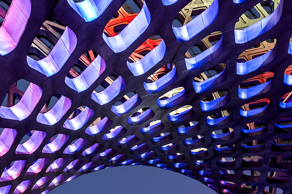 Abstract image of curved, perforated ceiling in colorful light